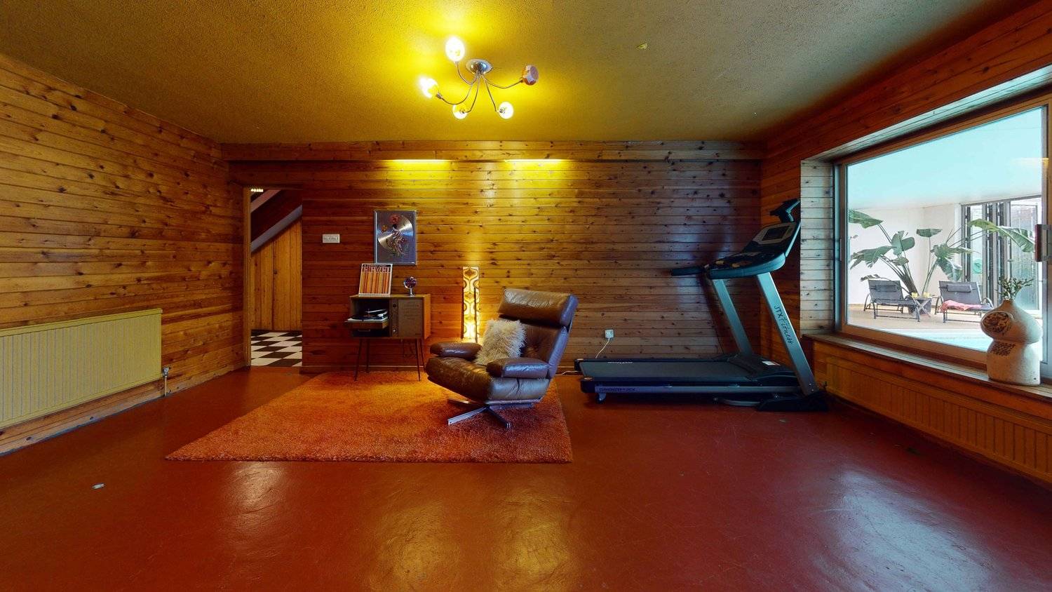Vintage lounge room corner with timber clad walls, shag pile area rug, and retro brown leather recliner, Love Locations SW16.