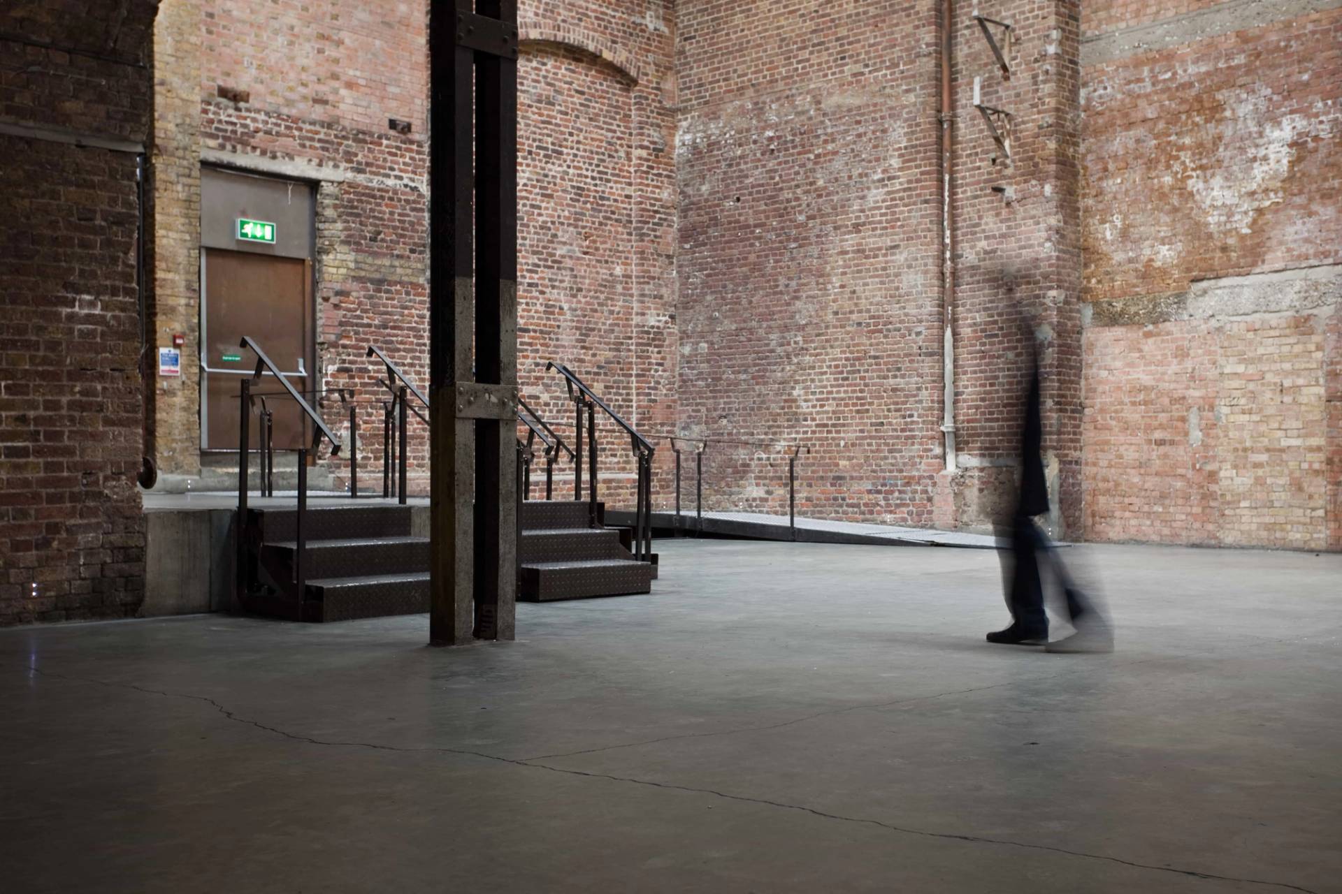 Raw industrial warehouse shoot location in Hackney EC2A via Love Locations, showcasing vaulted brick arches, steel support columns, and elevated access steps.