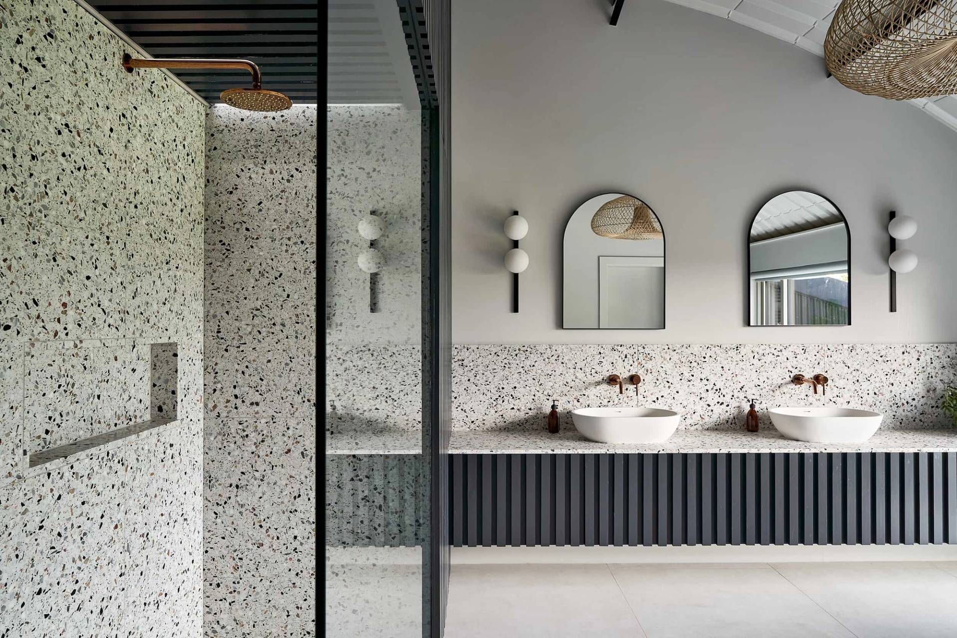 Modern wet room shower enclosure with terrazzo wall tiles, glass doors, and fluted dark panelling, Love Locations IP30.