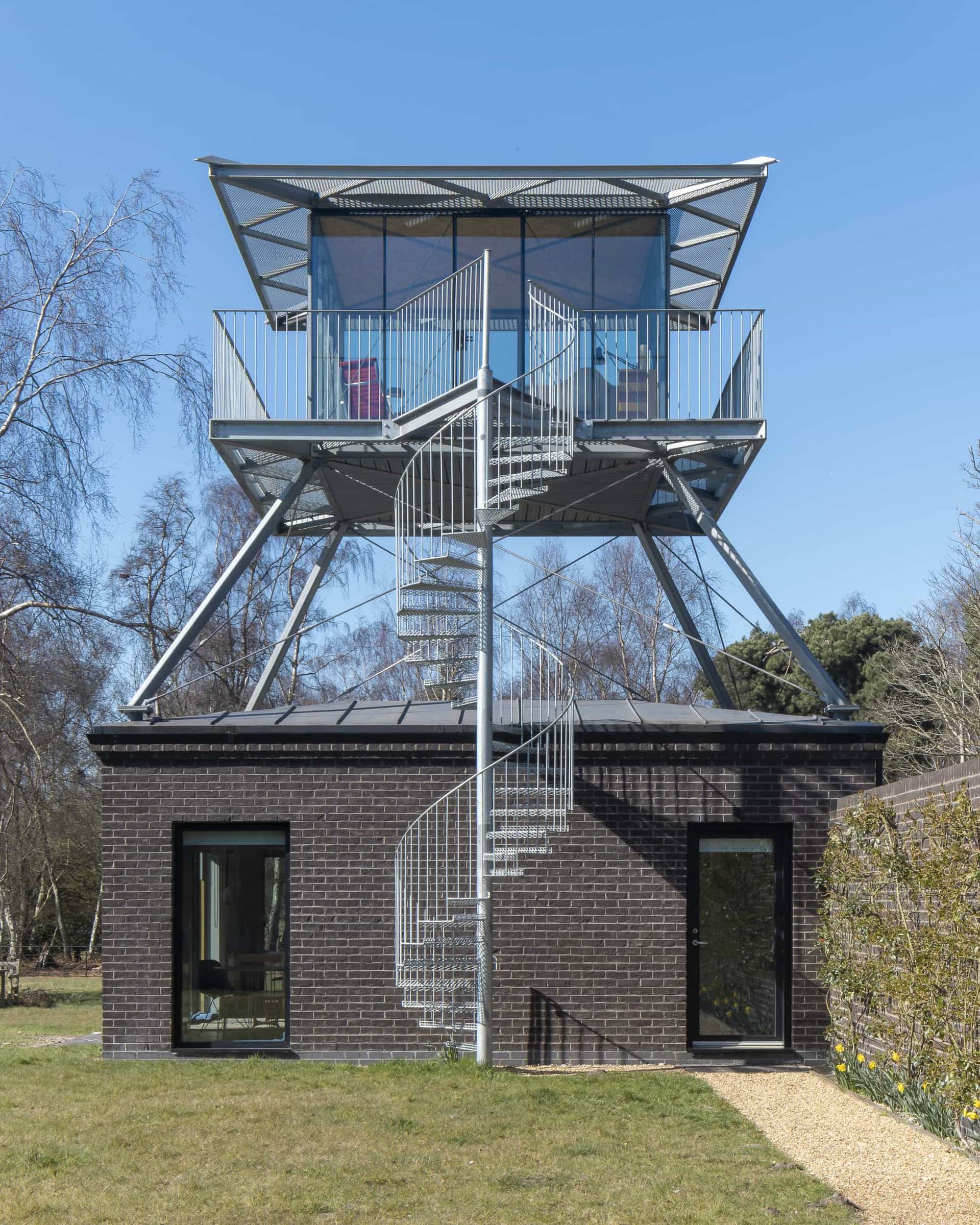 Architectural elevated glass lookout tower structure featuring spiral metal staircase and dark timber base, Love Locations IP17.