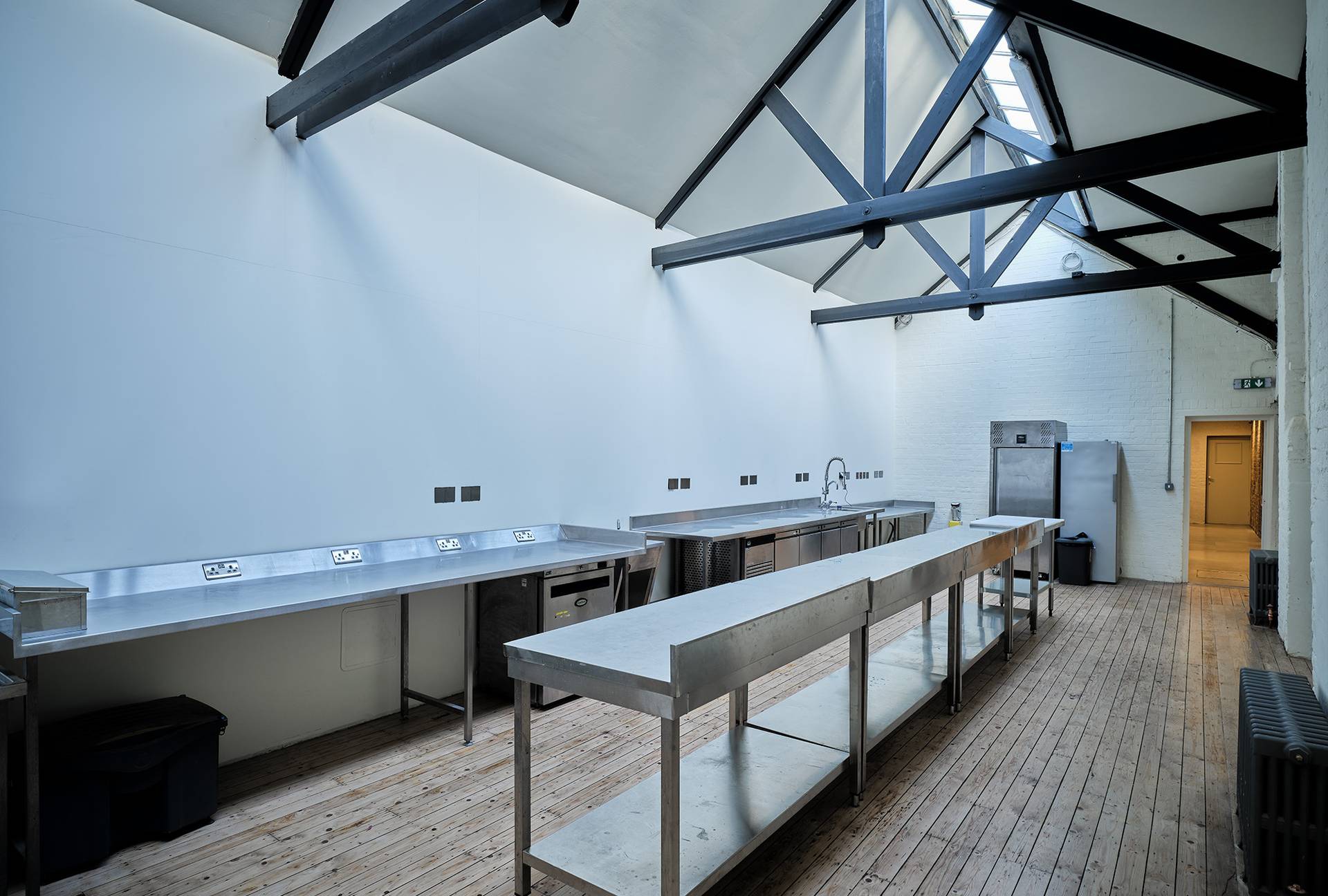 Professional stainless steel catering prep kitchen with commercial counters and industrial roof beams, ideal for event food prep, Love Locations E2.