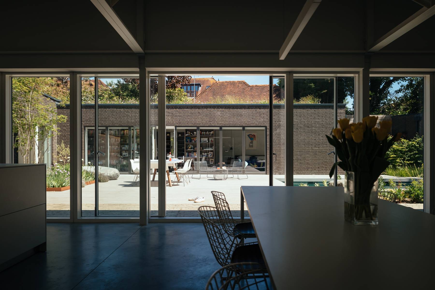 View through floor-to-ceiling glass doors looking from an open-plan room onto a swimming pool courtyard, Love Locations BN3.