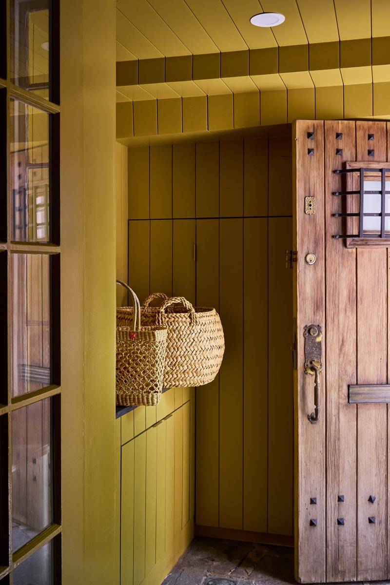 Rustic timber front entry door nook shoot venue with mustard yellow walls and hanging woven market baskets in Manhattan NY 10014 through Love Locations.