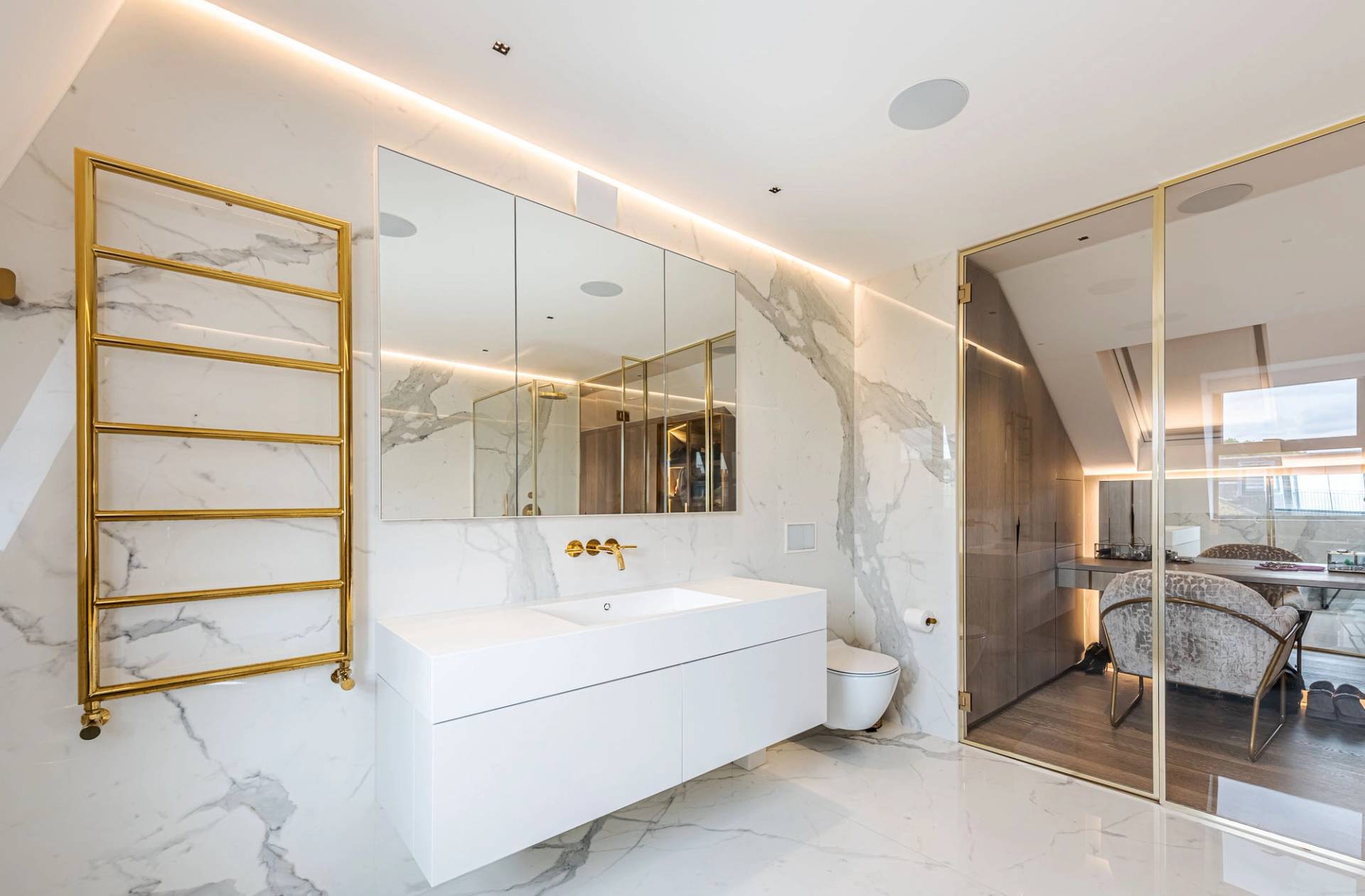 Sleek master bathroom vanity with double white sinks, illuminated mirrors, and gold brass fixtures, Love Locations SW11.
