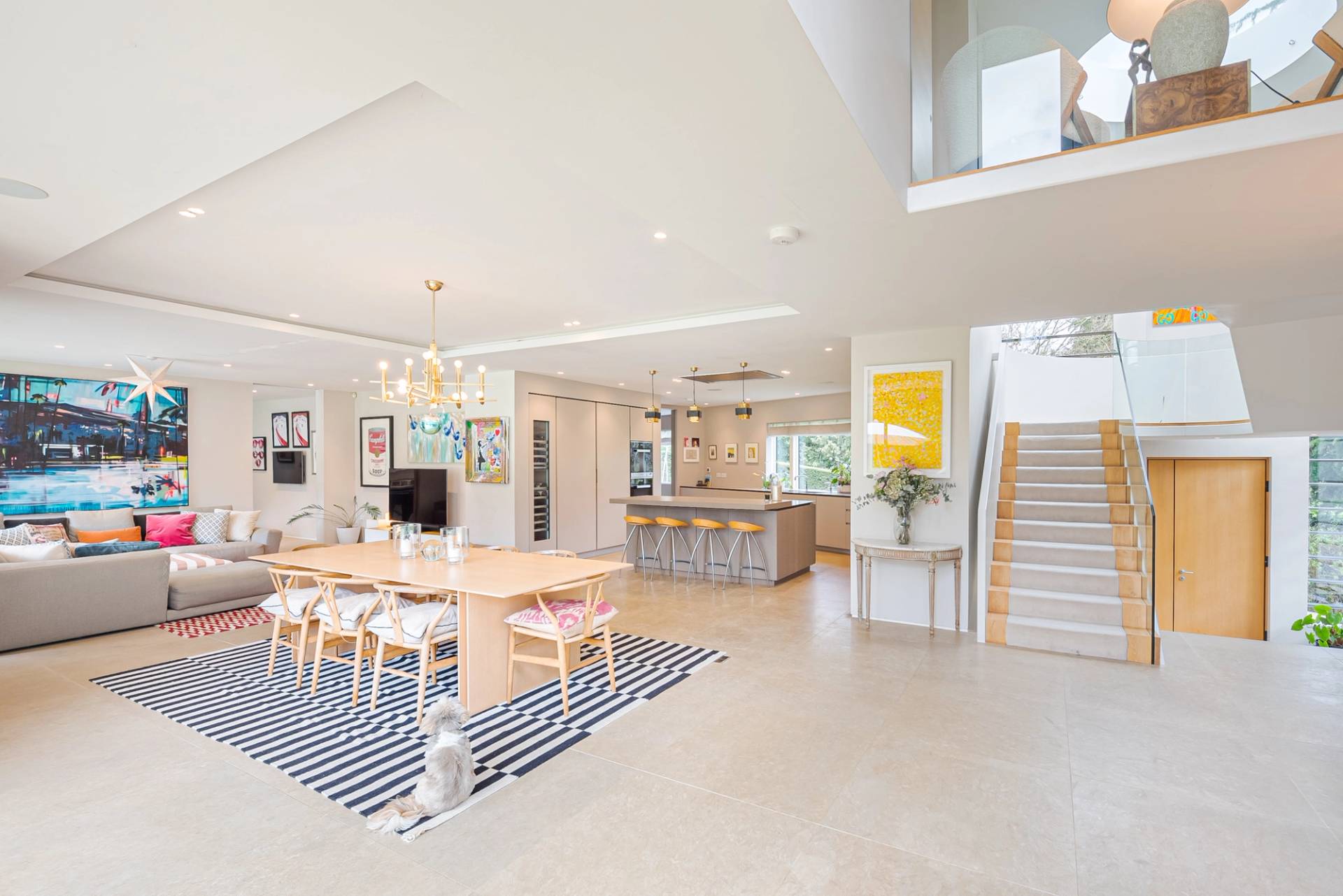 Sunlit open-plan living and kitchen area featuring floating staircases, oak dining furniture, and recessed ceiling lights in KT2, Love Locations.