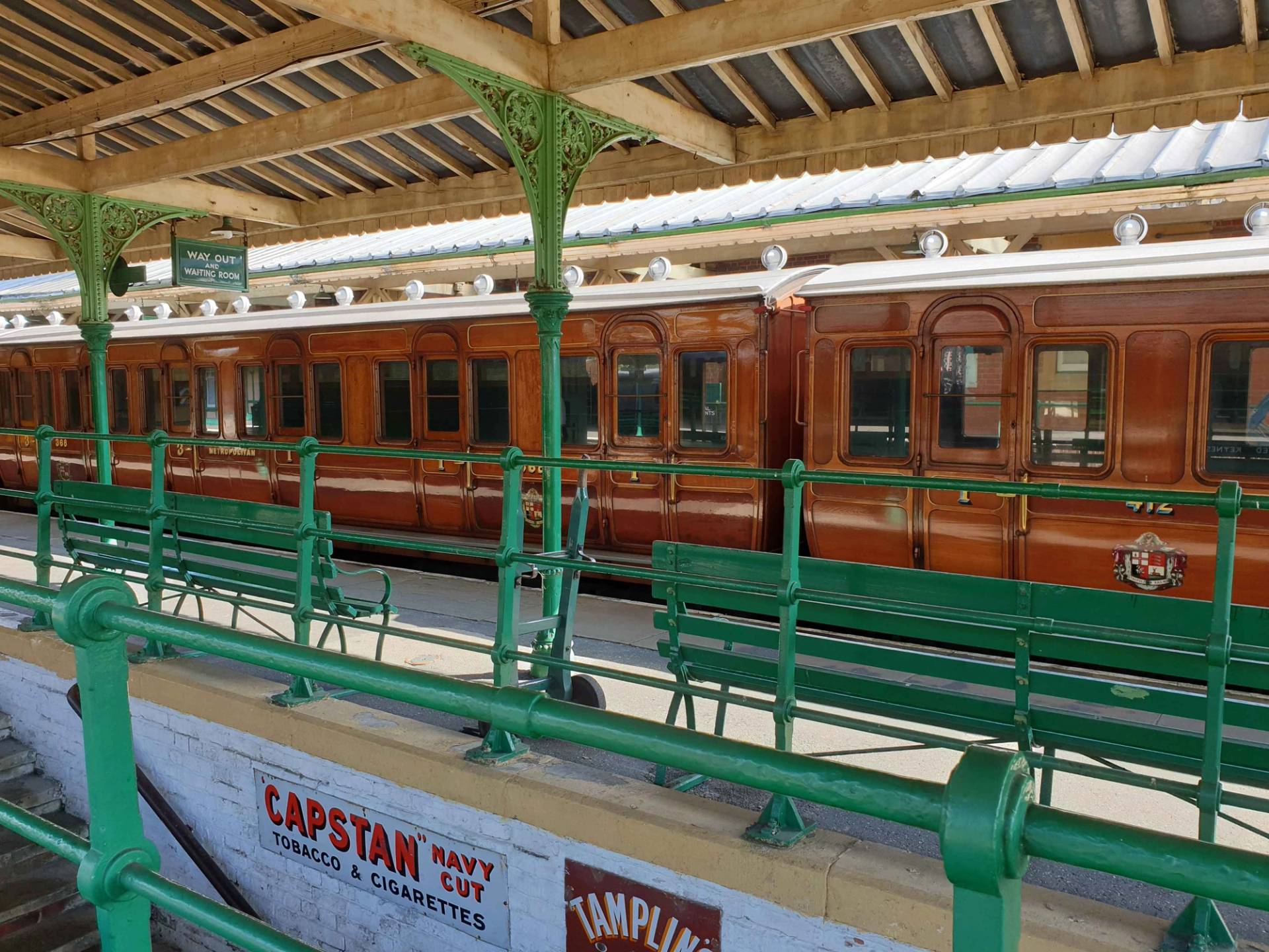 Platform waiting bench and green iron canopy supports beside a vintage railway carriage in Sussex, Love Locations TN22.