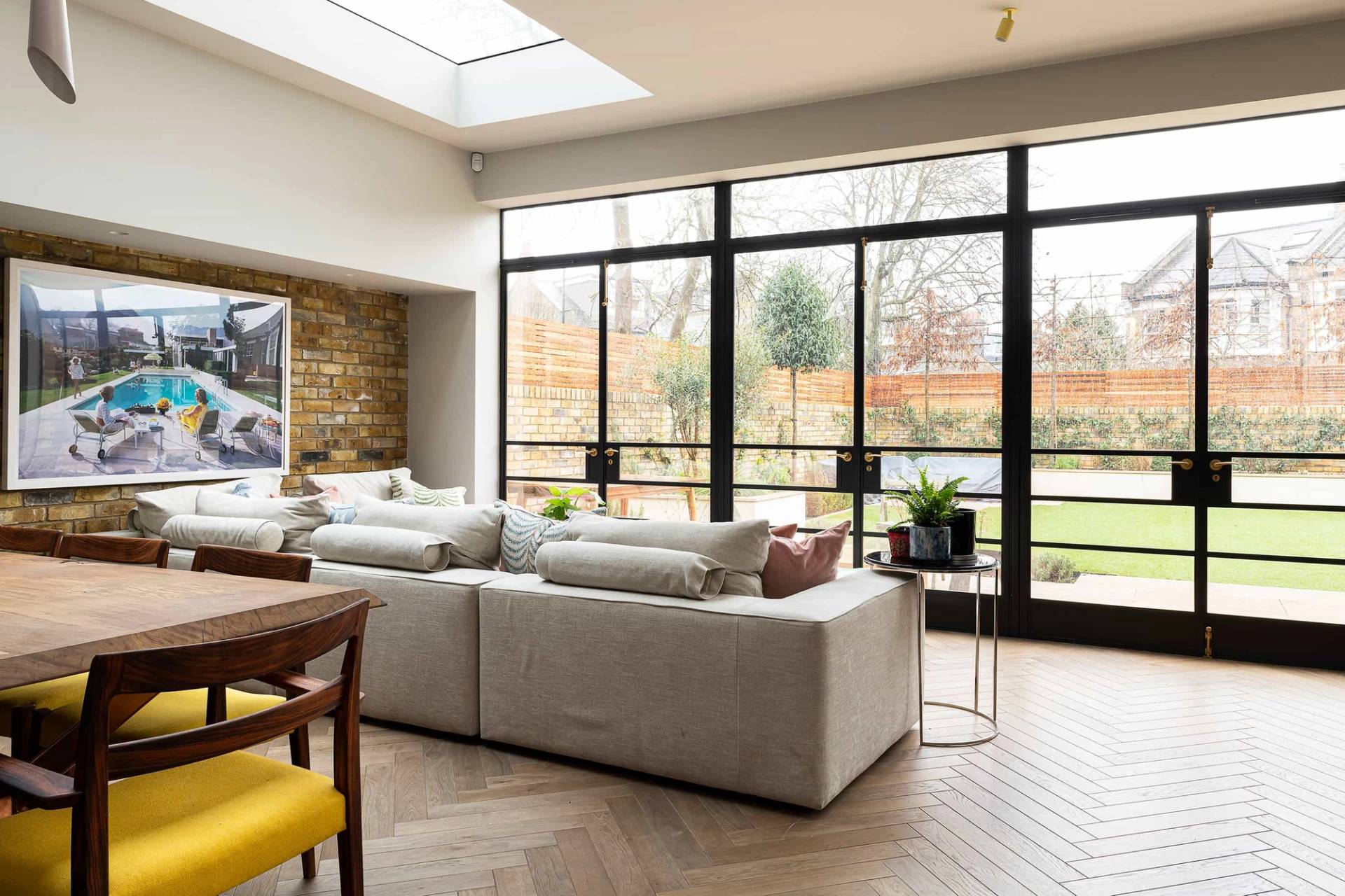 Open-plan living space featuring full-height black metal crittall sliding glass doors opening to a landscaped garden, ideal for indoor-outdoor lifestyle shoots, Love Locations NW6.