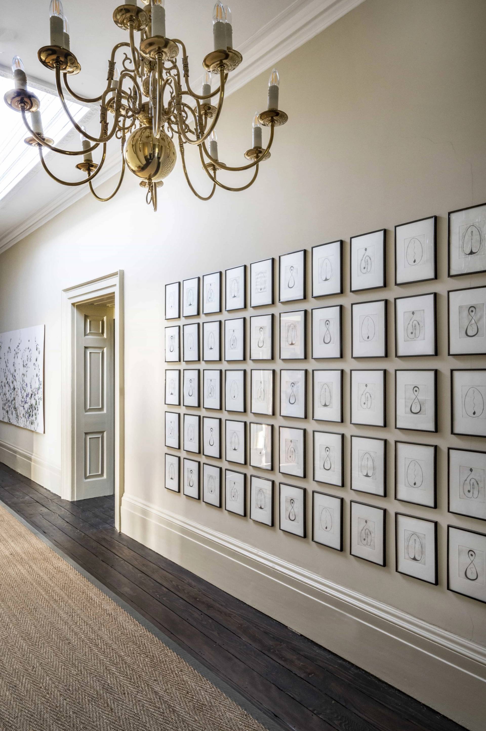 Impressive full-wall gallery grid of framed monochrome sketches in an upper hallway, ideal for creative brand backdrops, Love Locations LE7.