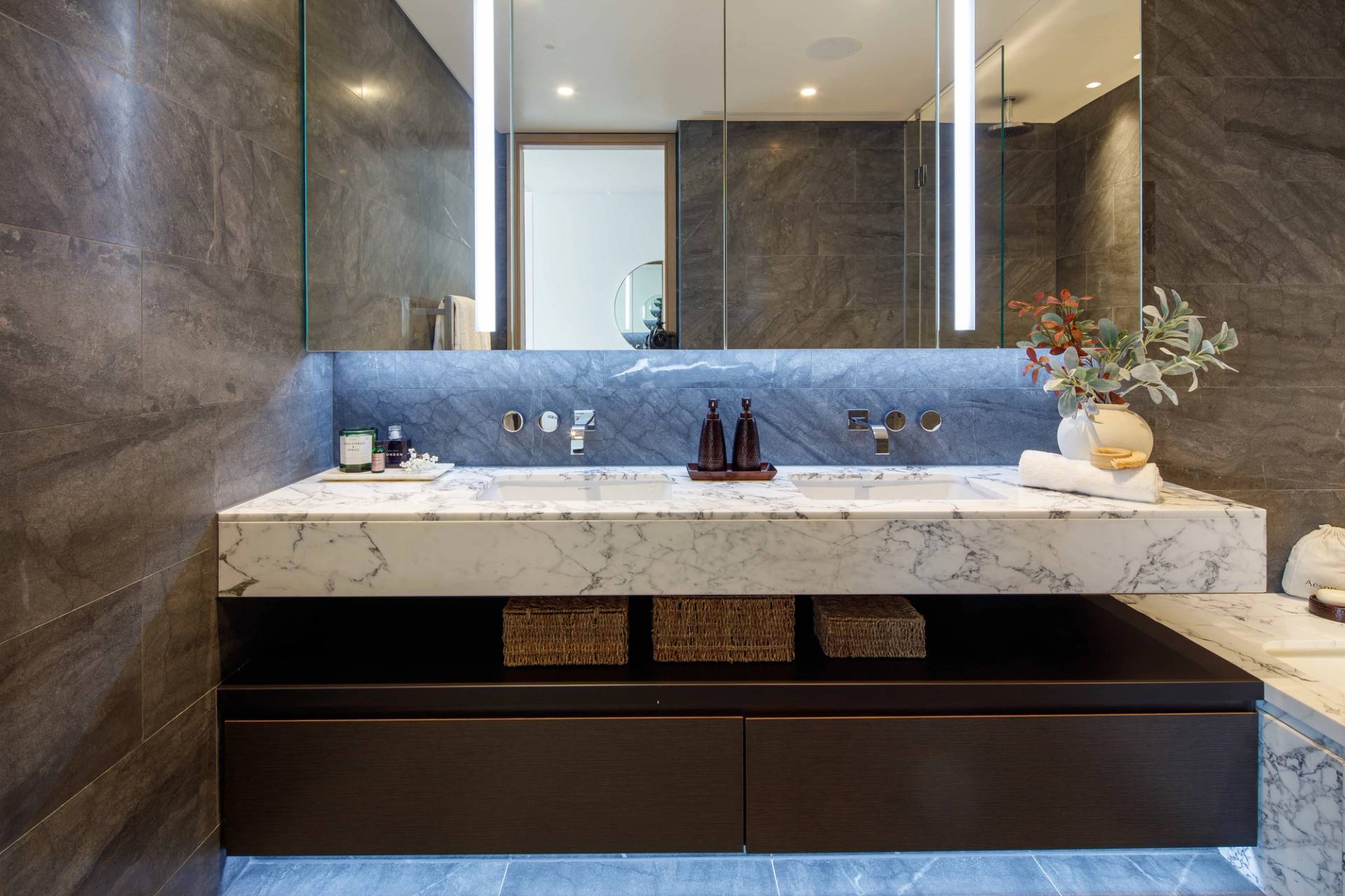 Luxury master ensuite bathroom featuring double marble sinks, dark vanity drawers, and LED under-cabinet illumination, ideal for premium skincare commercials, Love Locations EC2A.