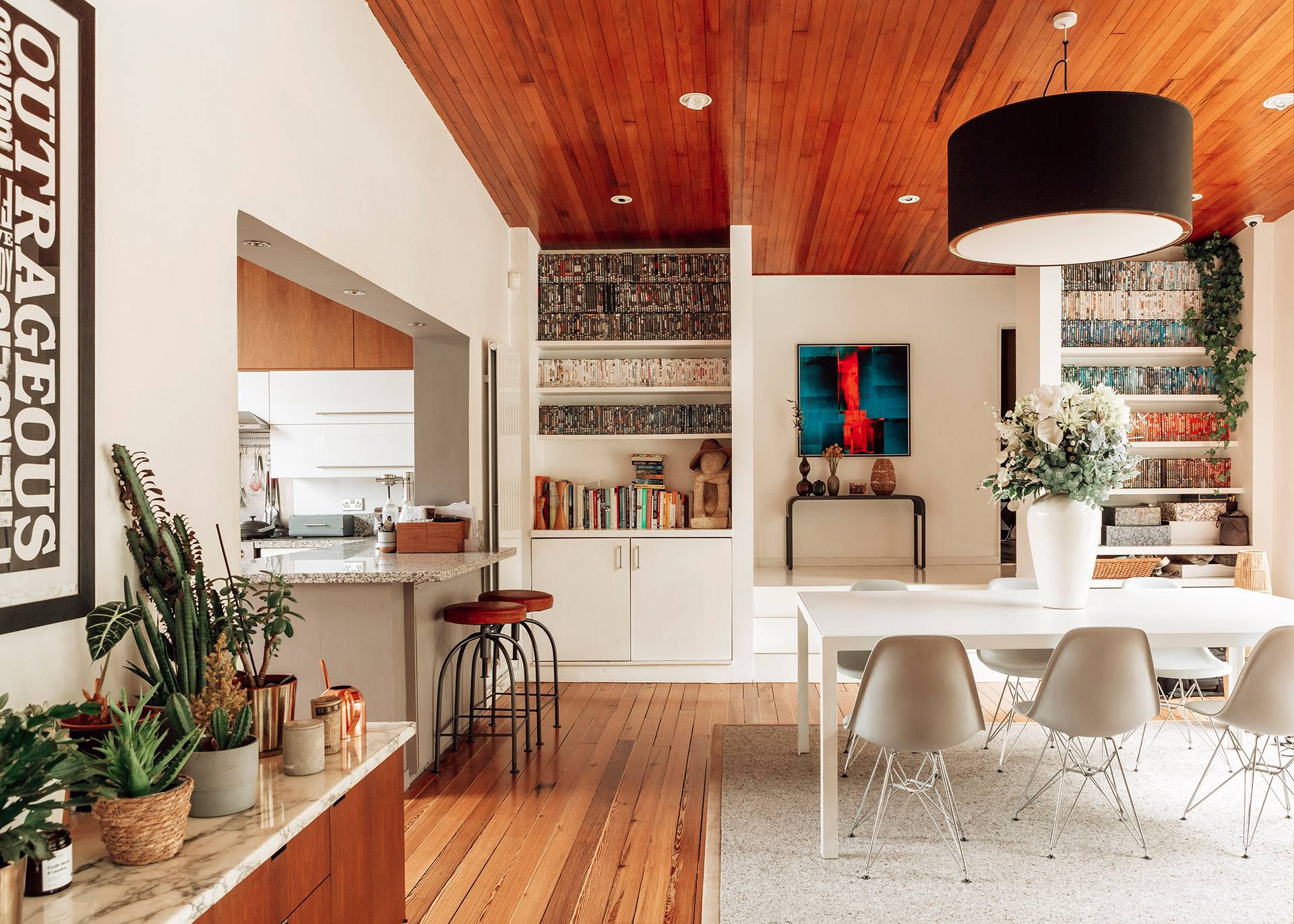 Open-plan mid-century kitchen and dining space featuring wooden ceiling panelling and sleek modern appliances, ideal for food media via Love Locations.