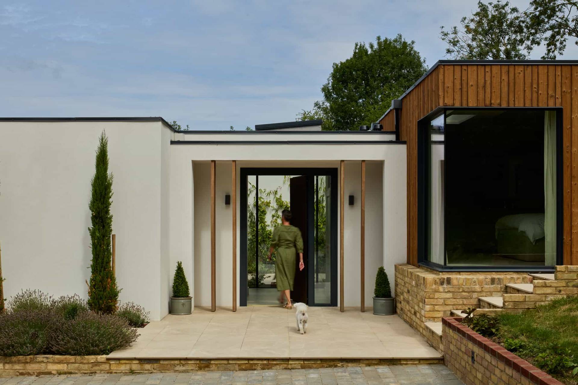 Entrance doorway of a luxury modern home with a model stepping out onto a stone paved portico, ideal for fashion editorial shoots via Love Locations KT22.