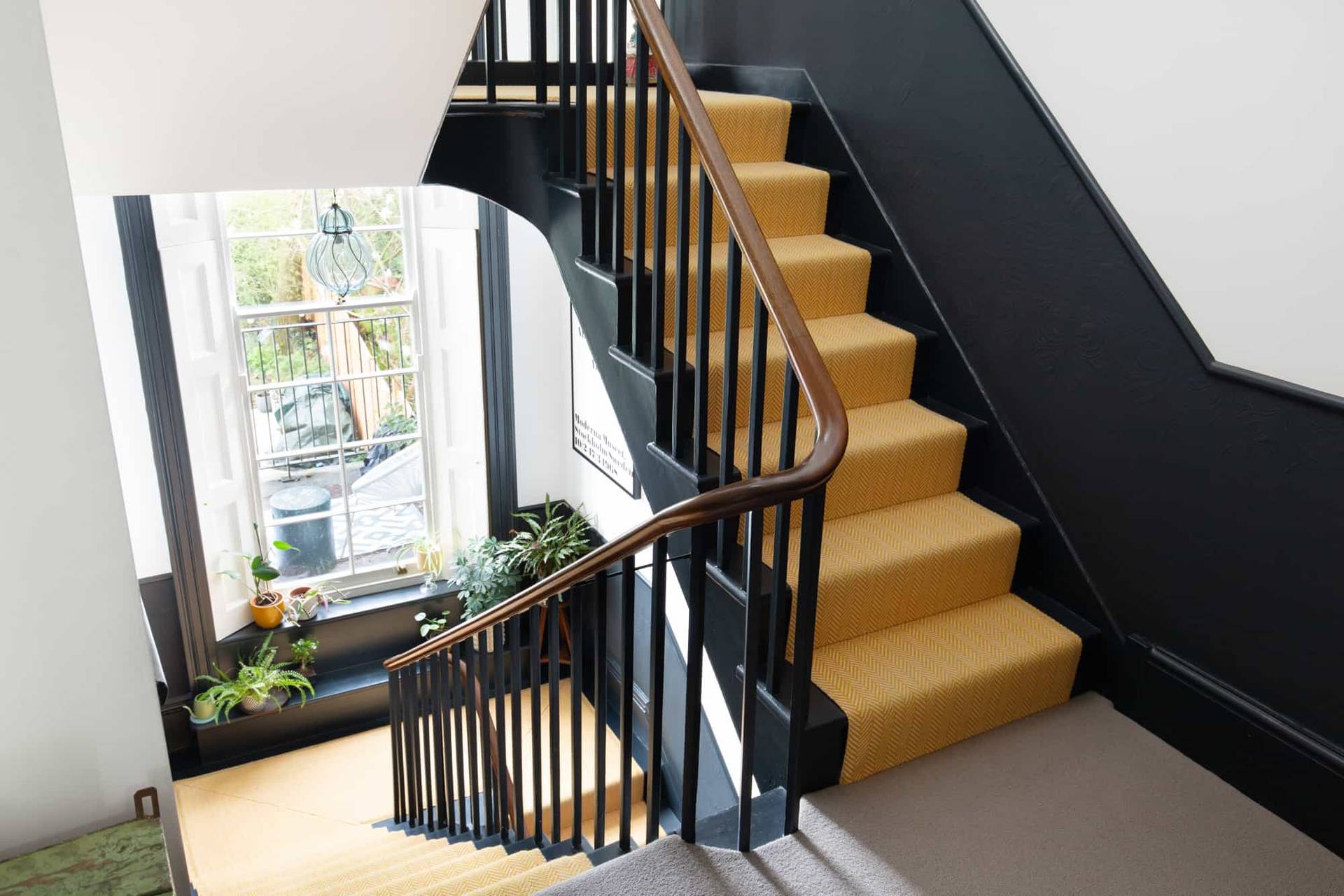 Staircase shoot location in Camberwell, SE5 featuring black balustrade and vibrant yellow carpet stair runner via Love Locations.