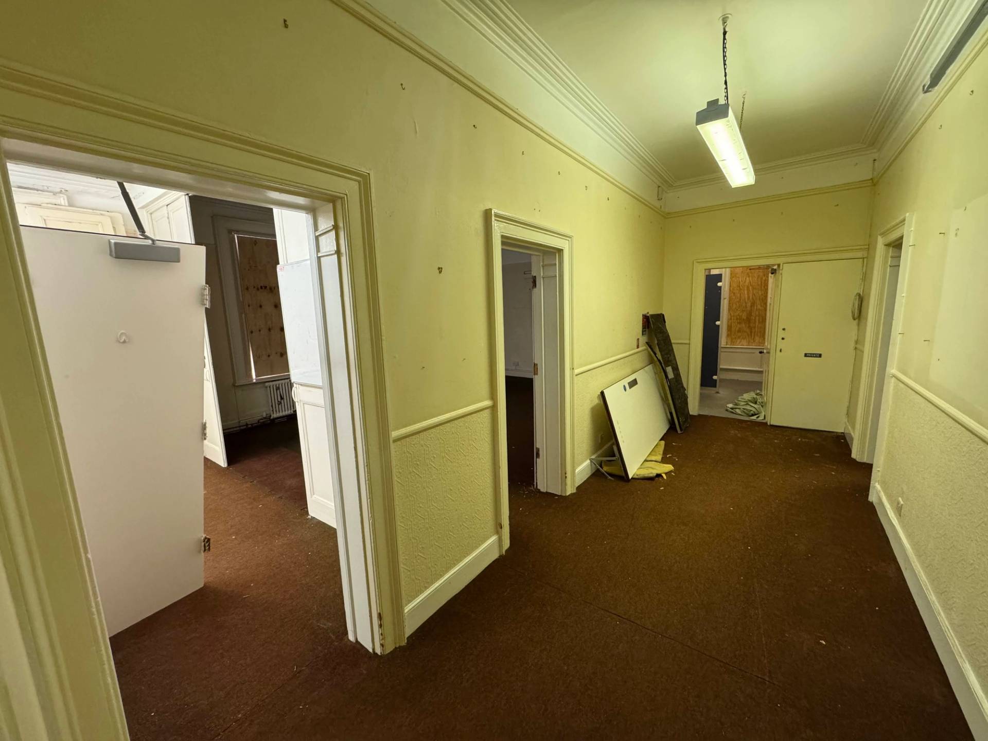 L-shaped institutional corridor junction with multiple doorways inside an abandoned mansion filming location, Love Locations.