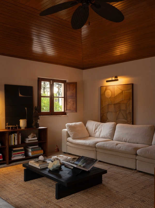 Cozy sitting room with white sofa, dark timber coffee table, small shuttered window, and warm lighting, Love Locations 2705-064.