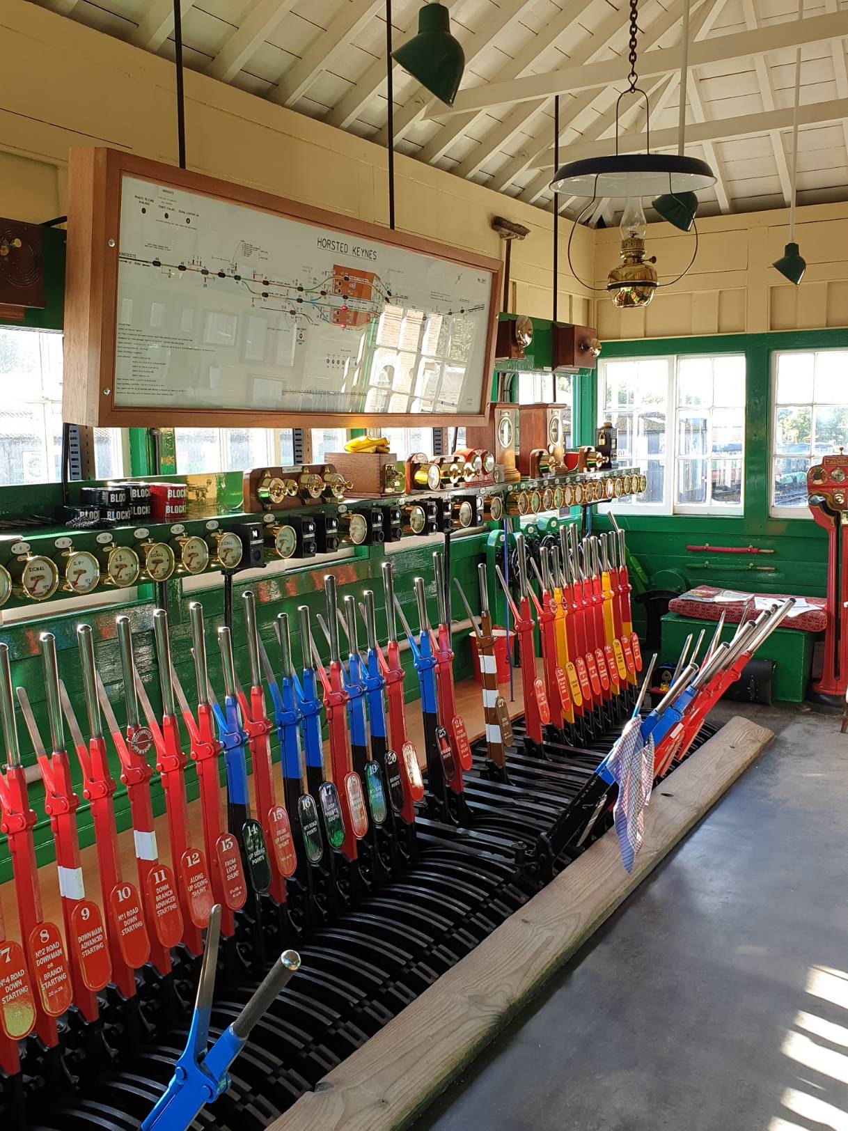 Traditional mechanical railway signal box lever frame with painted red, green, and blue levers in Sussex, ideal for documentary filming, Love Locations.