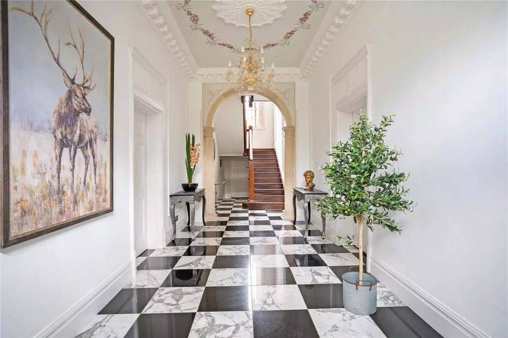 Dramatic grand entrance hall film location featuring black-and-white checkered marble tiled flooring, arched hall doorways, and a sweeping staircase through Love Locations.