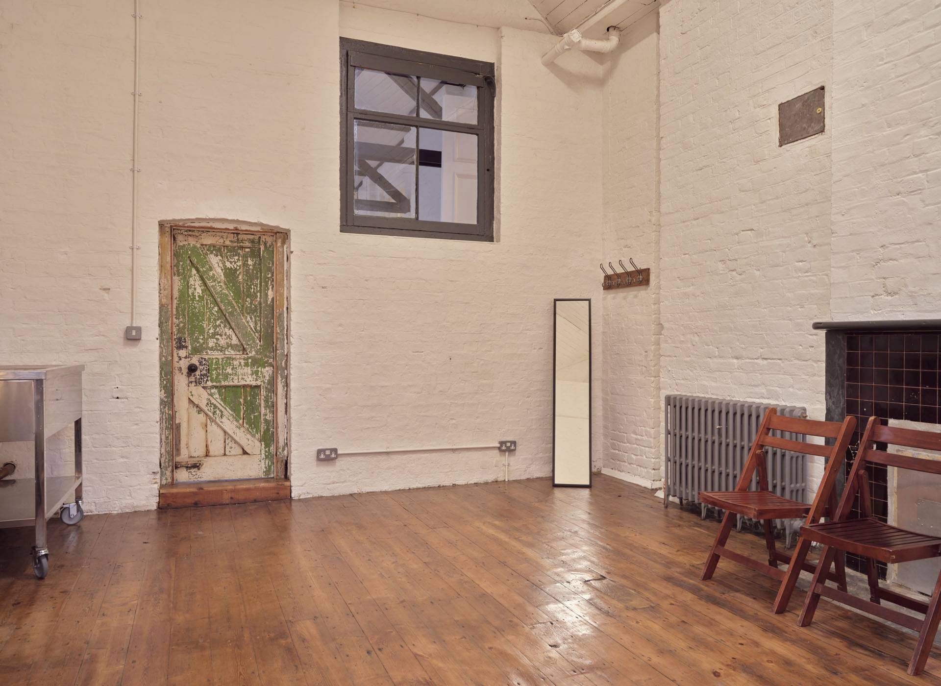 Dressing room or green room space featuring high ceilings, dark window frames, and wooden floorboards, Love Locations.