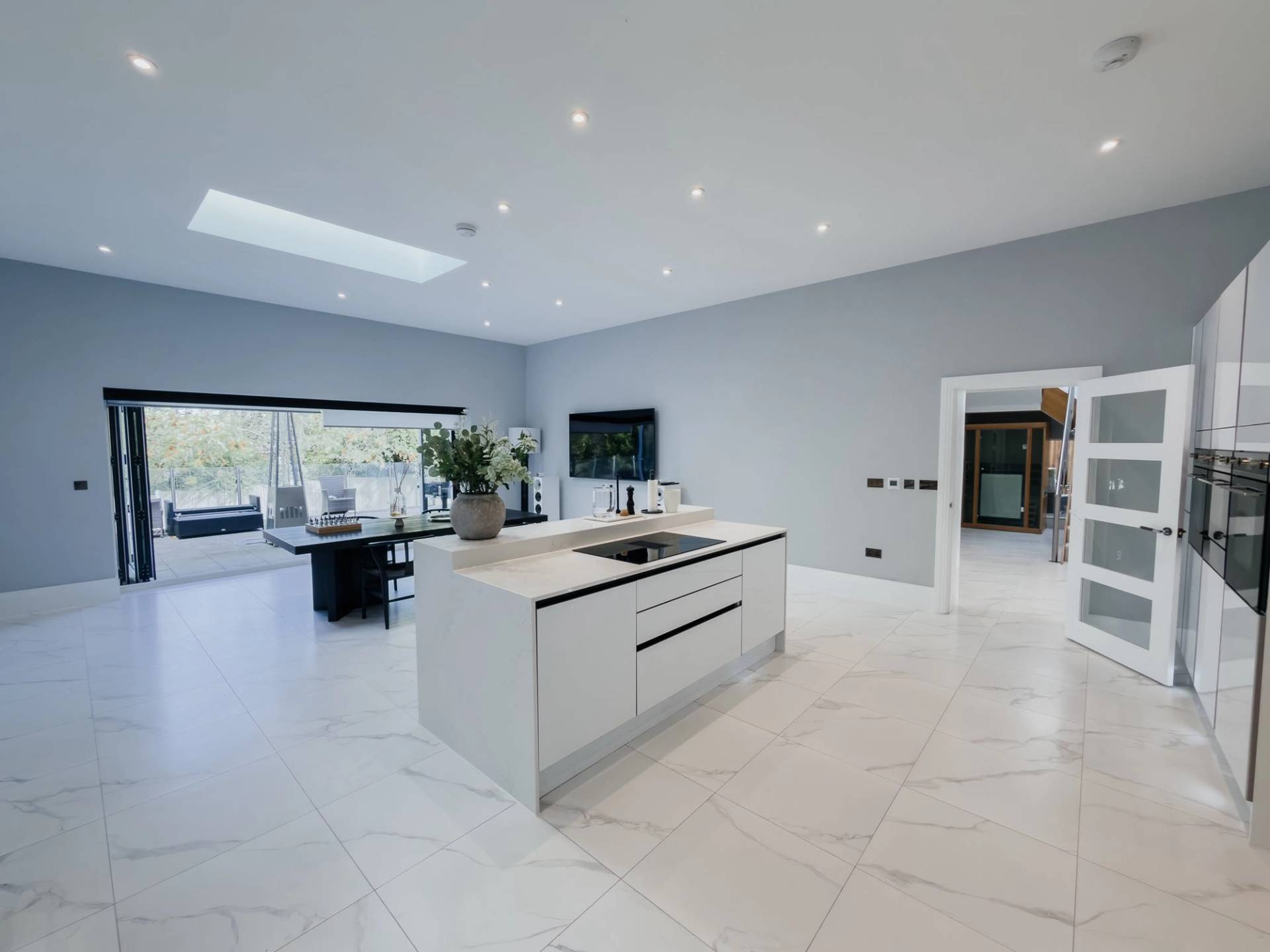 Contemporary white kitchen island shoot location in Barnet EN4 via Love Locations, showcasing sleek minimalist cabinetry, integrated appliances, and polished marble flooring.