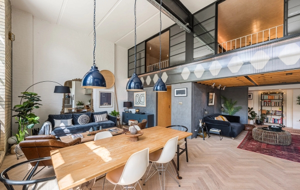 Open-plan living space with a wooden dining table, exposed steel beams, and a mezzanine balcony level, Love Locations SE1.
