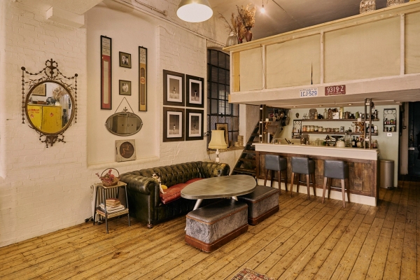Vintage industrial lounge seating area featuring a green leather sofa, wooden coffee table, and eclectic retro decor, ideal for music video shoots via Love Locations.