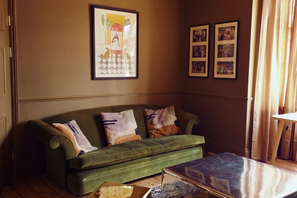 Moody, stylish living room featuring a rich green velvet sofa, patterned cushions, and dark wood furniture, ideal for upscale fashion and music video shoots, Love Locations.