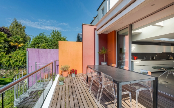 Sunlit wooden outdoor balcony deck furnished with a contemporary dining set, ideal for upscale patio furniture brand advertising, Love Locations London.