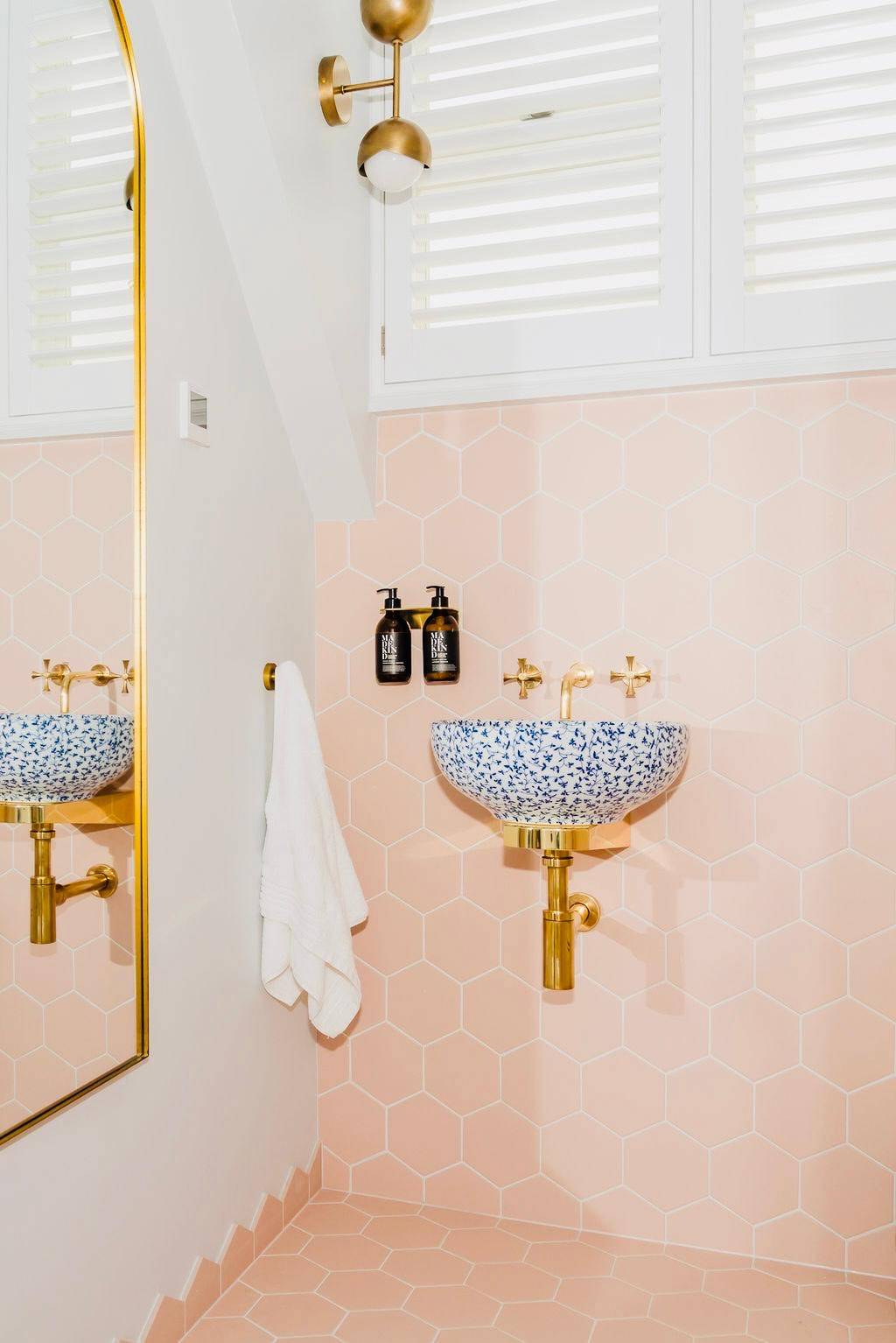 Powder room bathroom with terrazzo vessel sink, pink walls, and brass wall-mounted taps, Love Locations TW11.