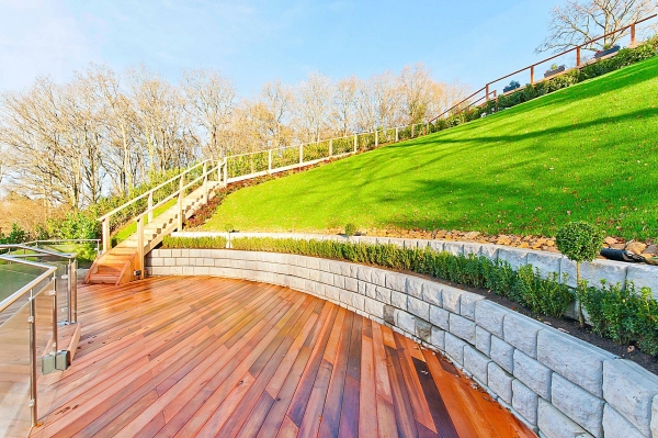 Tiered architectural garden lawn featuring a curving timber deck path and stone retaining walls, unique outdoor shoot space via Love Locations.