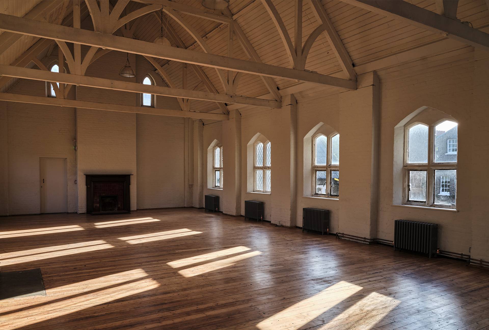 Sunlit hall corner with sunlight streaming through arched windows onto wooden floorboards, ideal for video content creation, Love Locations.