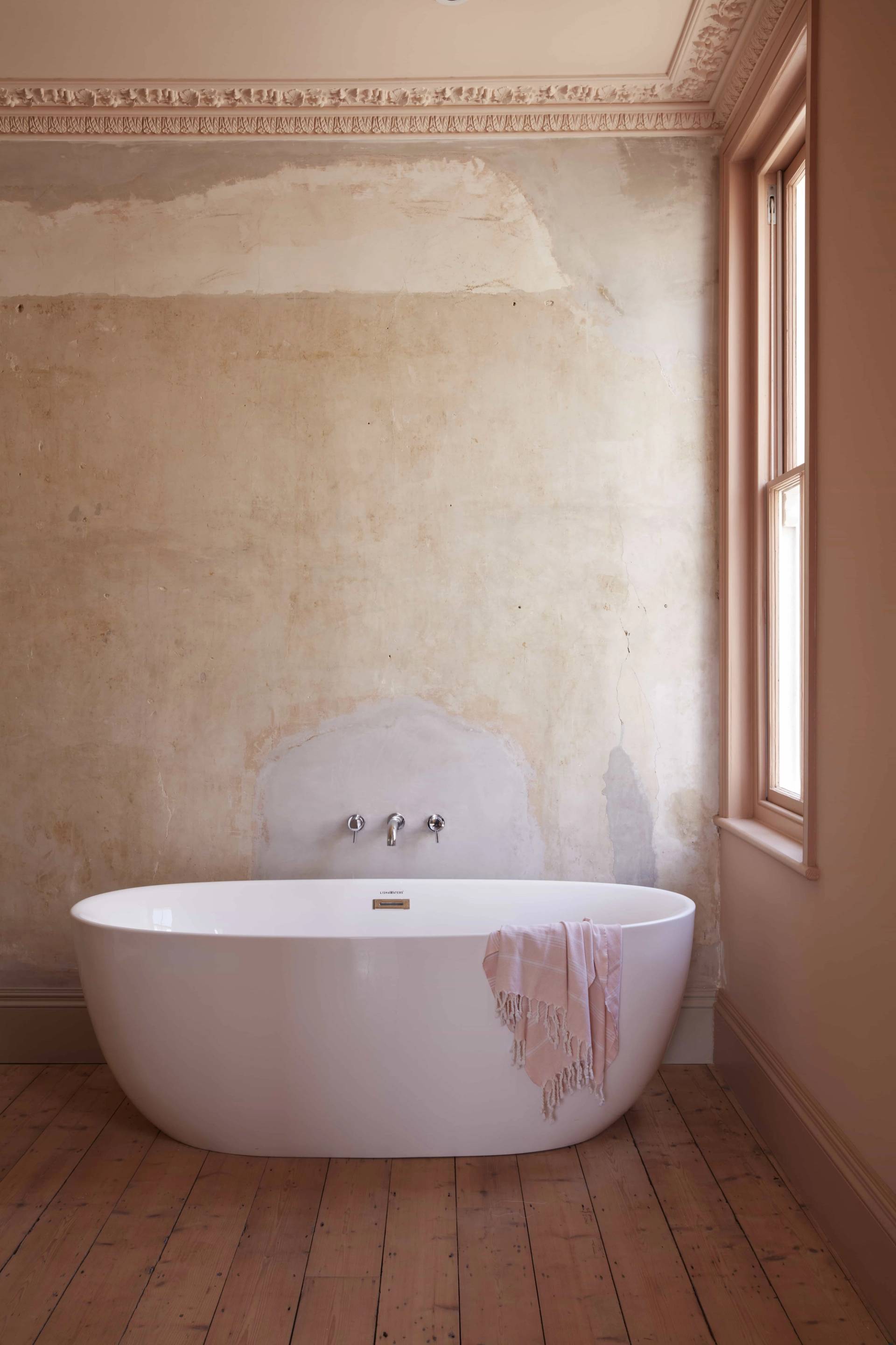 Minimalist plaster bathroom featuring a white oval freestanding tub against rustic plaster walls, ideal for luxury wellness and skincare campaigns, Love Locations TN34.