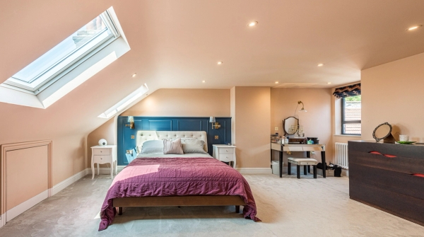 Converted loft bedroom shoot space with sloped ceilings, skylight windows, and a deep blue paneled feature wall, Love Locations.