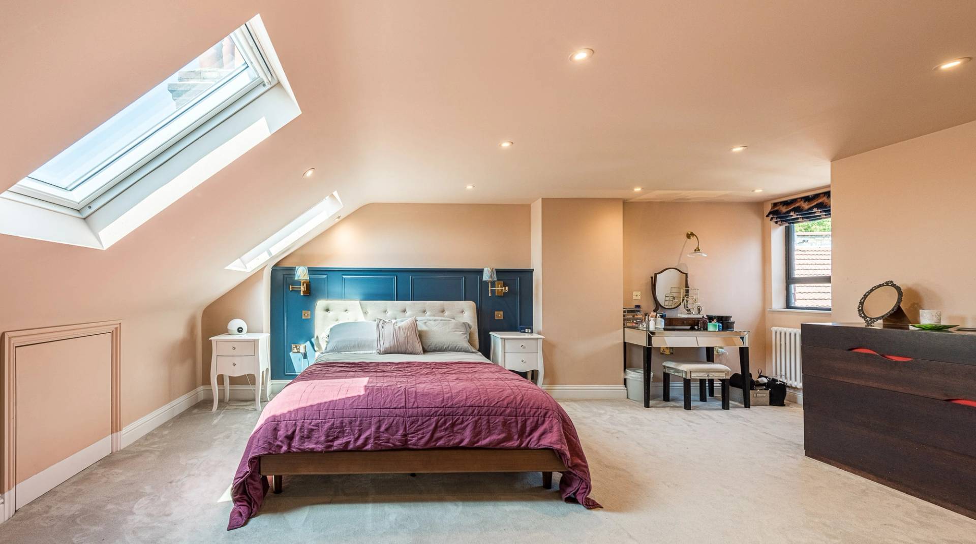 Converted loft bedroom shoot space with sloped ceilings, skylight windows, and a deep blue paneled feature wall, Love Locations.
