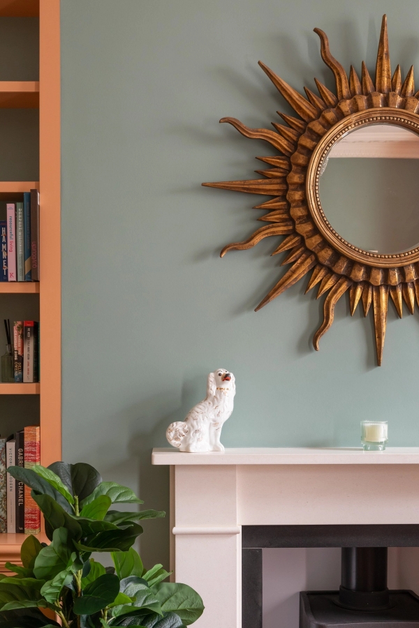 Detail shot of a green living room mantlepiece with a large gold sunburst mirror, a premium shoot location in Westminster SW1V by Love Locations.