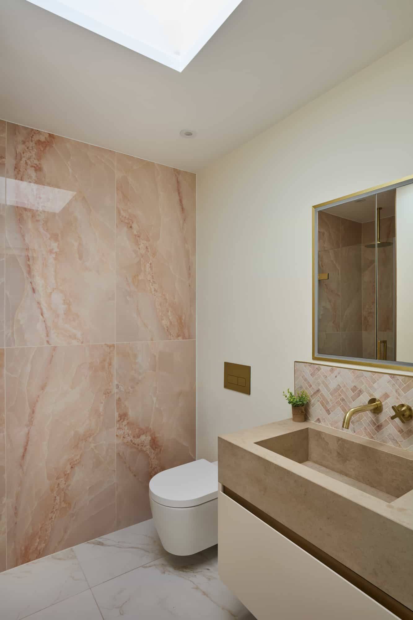 Modern powder room featuring pink marble wall tiles, custom stone vanity basin, and brass fixtures, ideal for beauty brand shoots, Love Locations KT22.