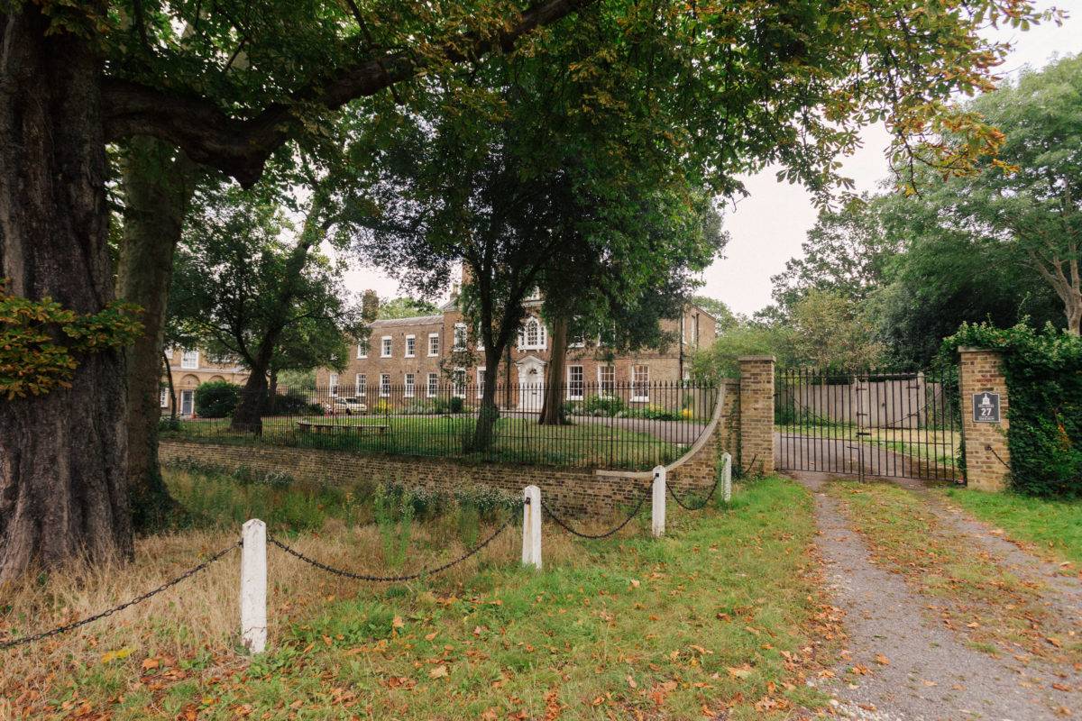 Estate entrance driveway lined by iron railings and mature leafy trees in Dulwich, SE15, Love Locations.