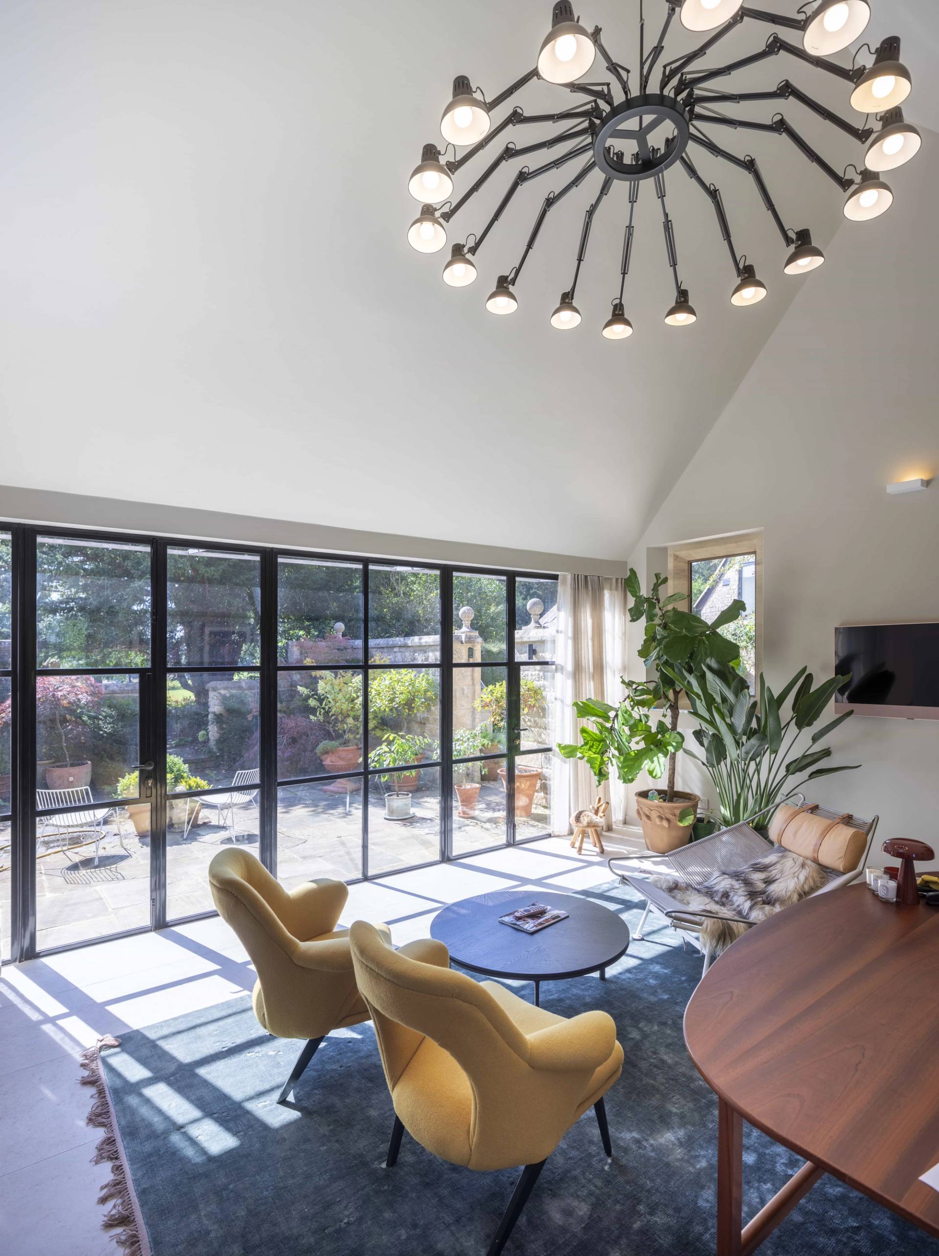 Contemporary sunroom extension with full-height black crittall windows, yellow armchairs, and skylight, Love Locations OX7.