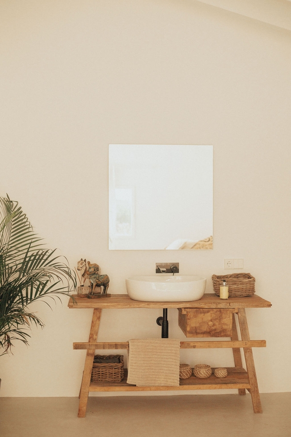Minimalist bathroom vanity area with round vessel sink, wooden table, and square mirror, Love Locations 07630.