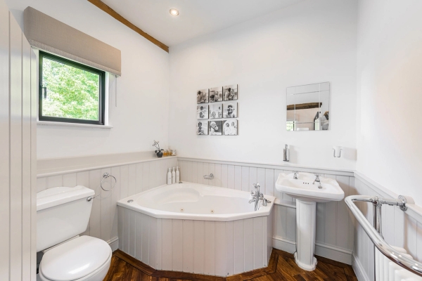 Classic white wood-paneled bathroom setting with a large corner bathtub for commercial lifestyle photography, Love Locations.