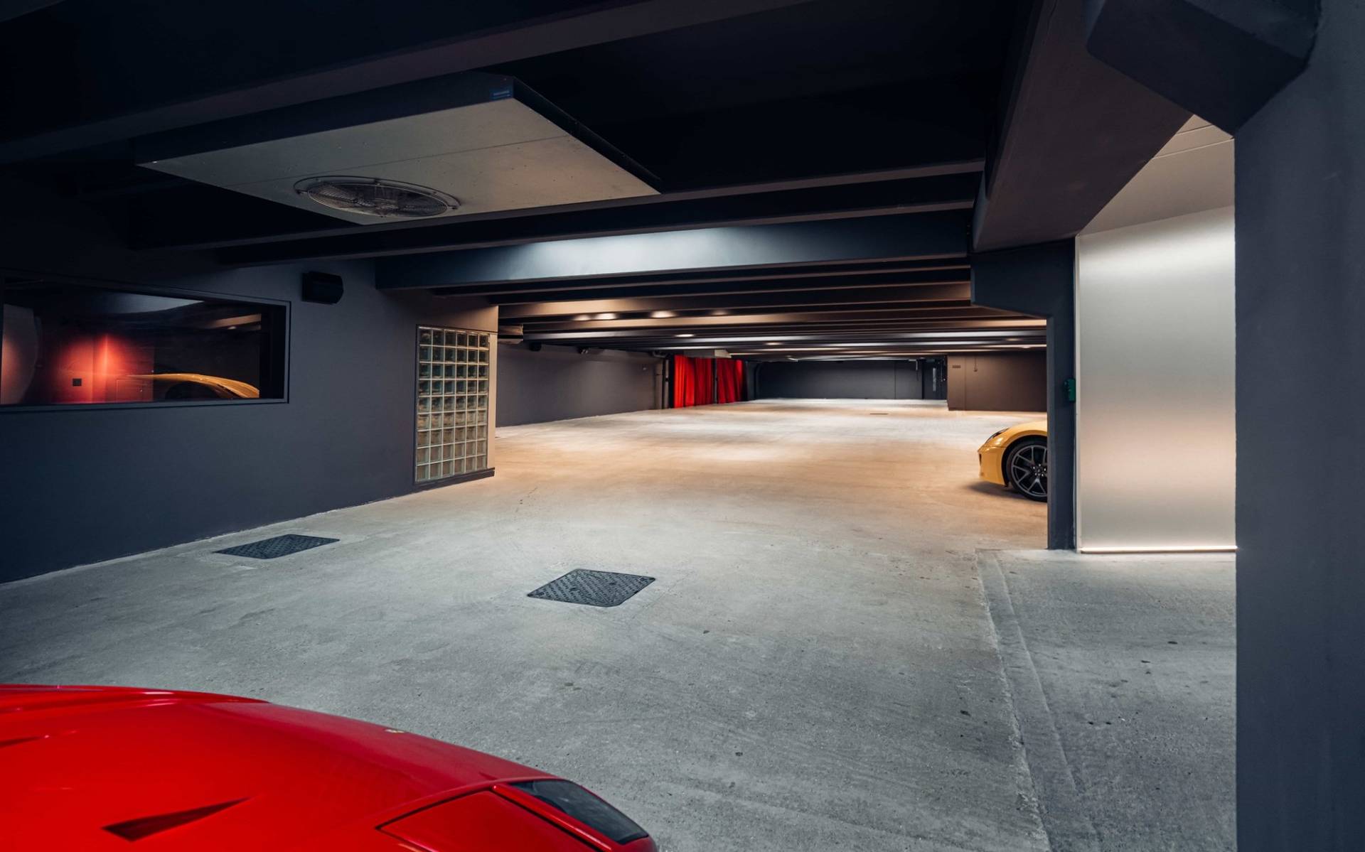 Dark industrial basement space featuring glass block walls, concrete pillars, and rich red velvet curtains in Brentford TW8 from Love Locations.