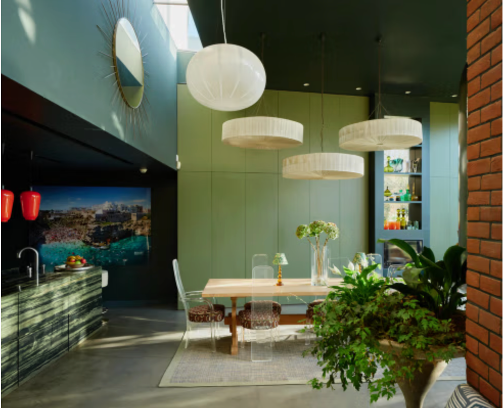 Contemporary dining space at Copse House with olive-green walls, dramatic dark ceiling, oversized pendant lights and floor-to-ceiling glazing.
