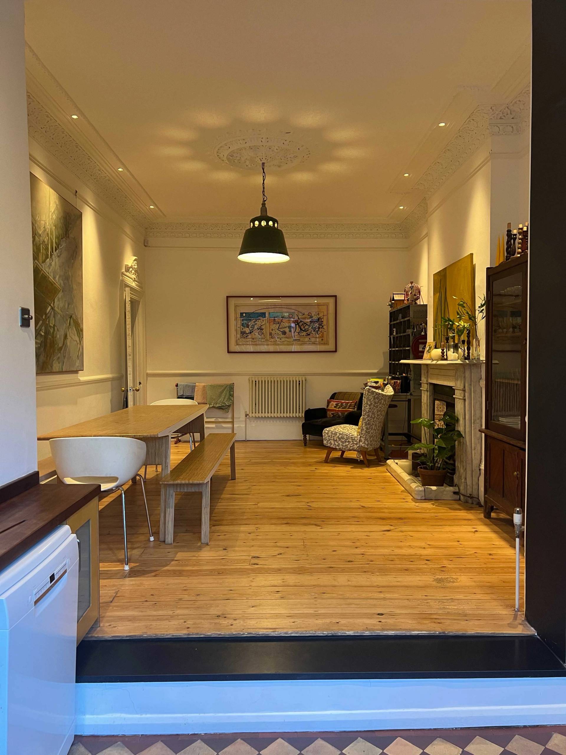 Spacious dining hall with stripped floorboards, original fireplace, and warm overhead pendant light in South Camberwell, Love Locations SE5.