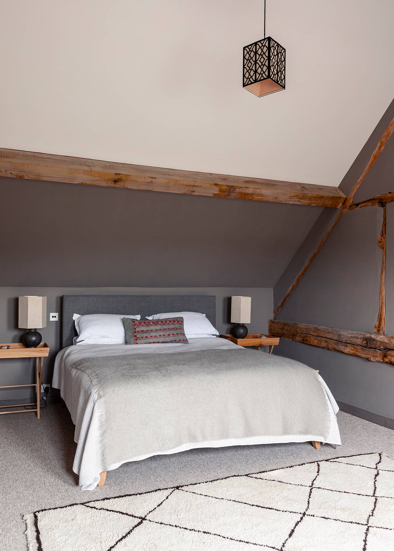 Attic bedroom suite featuring exposed timber wall beams, neutral linen bedding, and grey walls, Love Locations SN8.