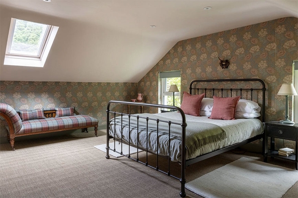 Loft bedroom at Glenstriven with iron-frame bed, patterned wallpaper and skylight window