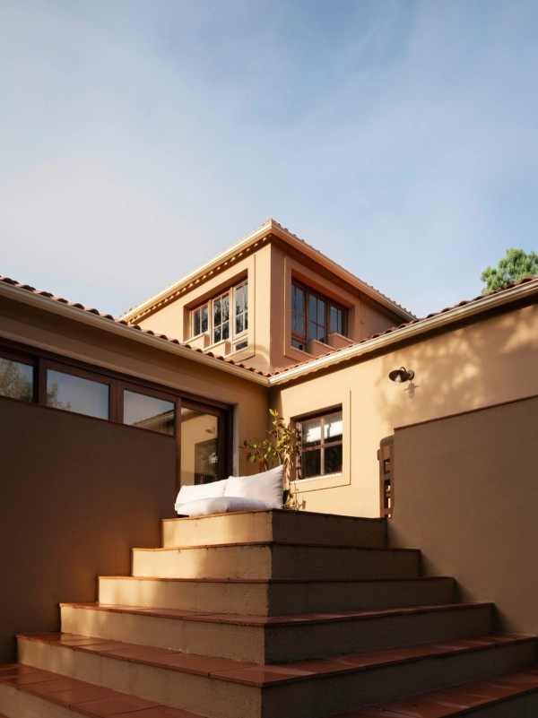 Exterior terrace steps leading up to an ochre plaster villa facade with terracotta tile roof, Love Locations 2705-064.