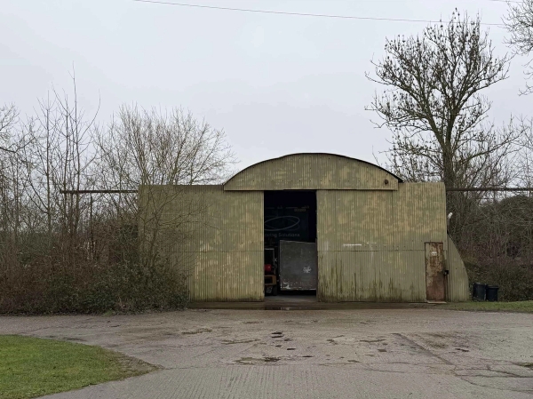 Surviving WWII woodland storage warehouse building surrounded by trees, ideal for mystery or thriller film scene backdrops, Love Locations NN17.