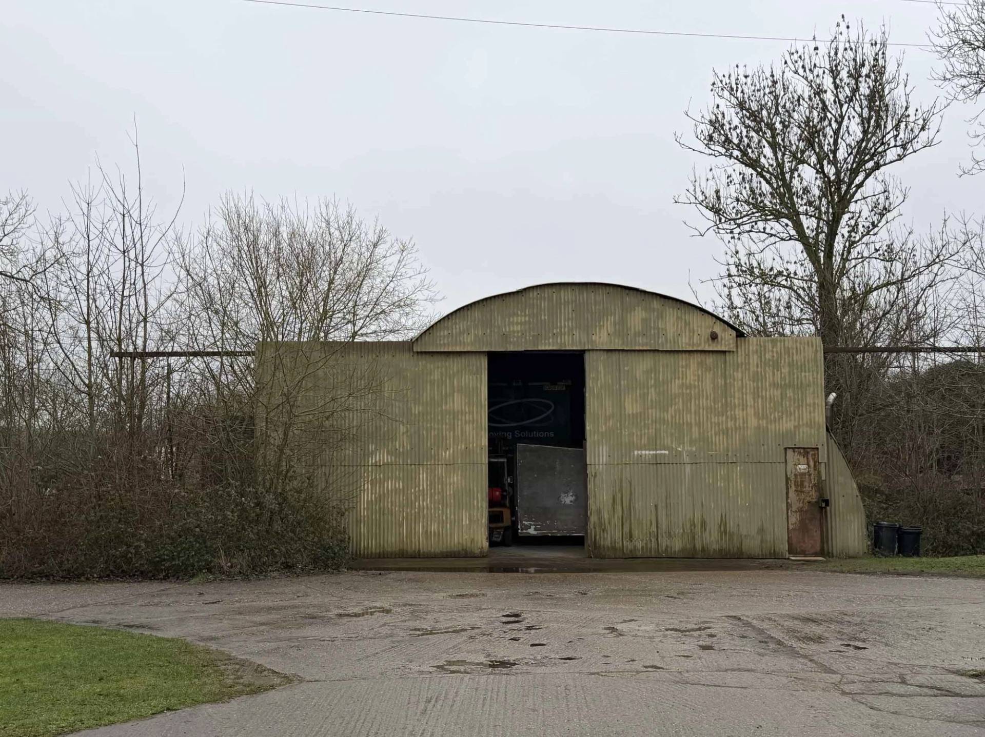 Surviving WWII woodland storage warehouse building surrounded by trees, ideal for mystery or thriller film scene backdrops, Love Locations NN17.