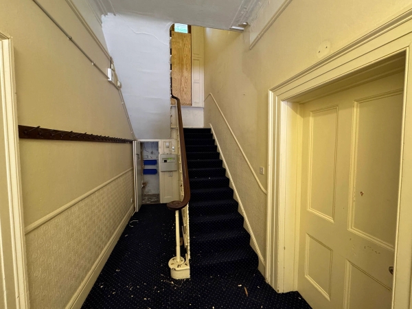 Period staircase location featuring black carpeted steps and a decorative cream vintage balustrade railing, Love Locations.