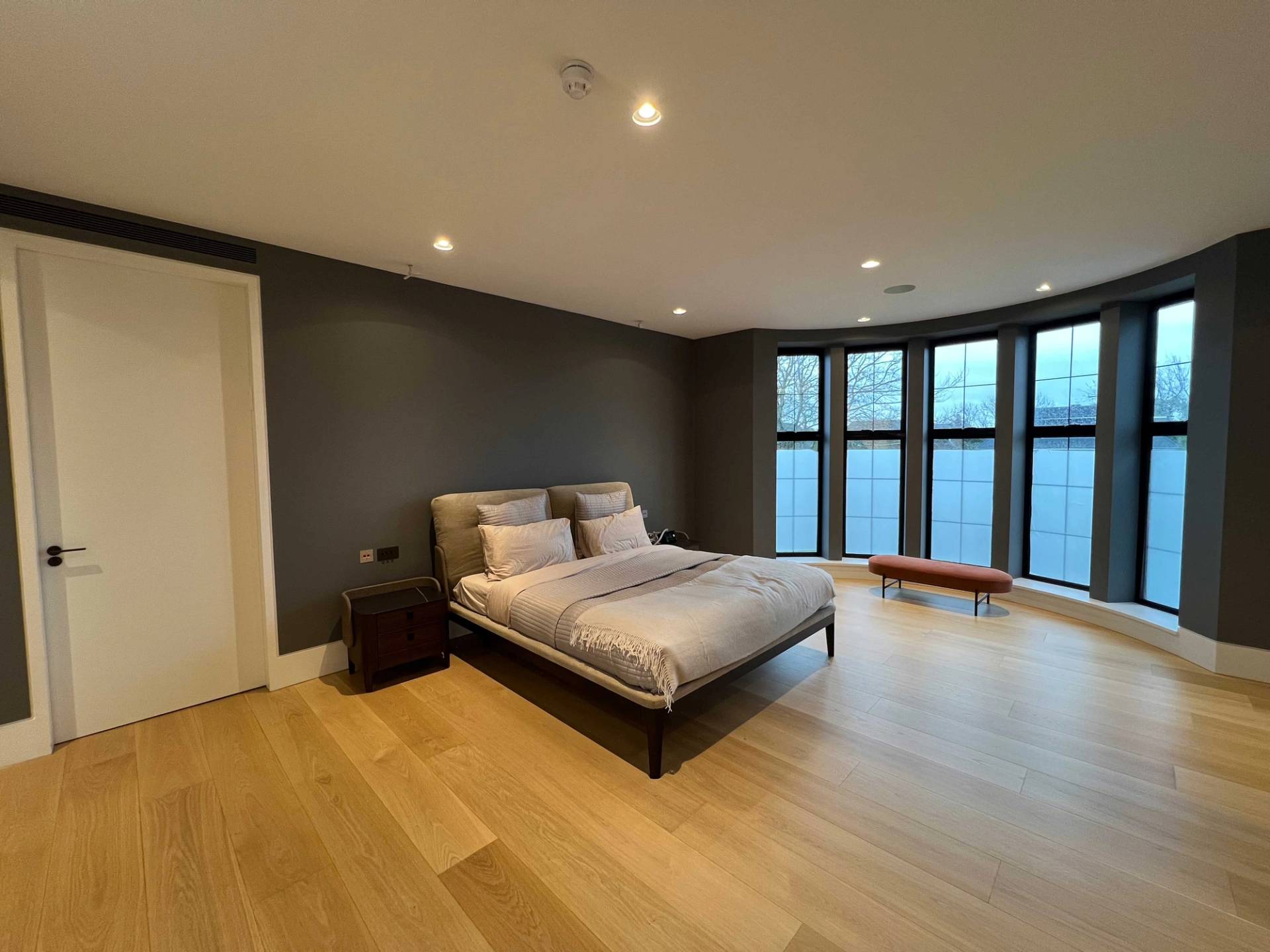 Spacious master bedroom location featuring light oak flooring, black bay windows, and neutral bed styling, ideal for mattress brand advertising, Love Locations N3.