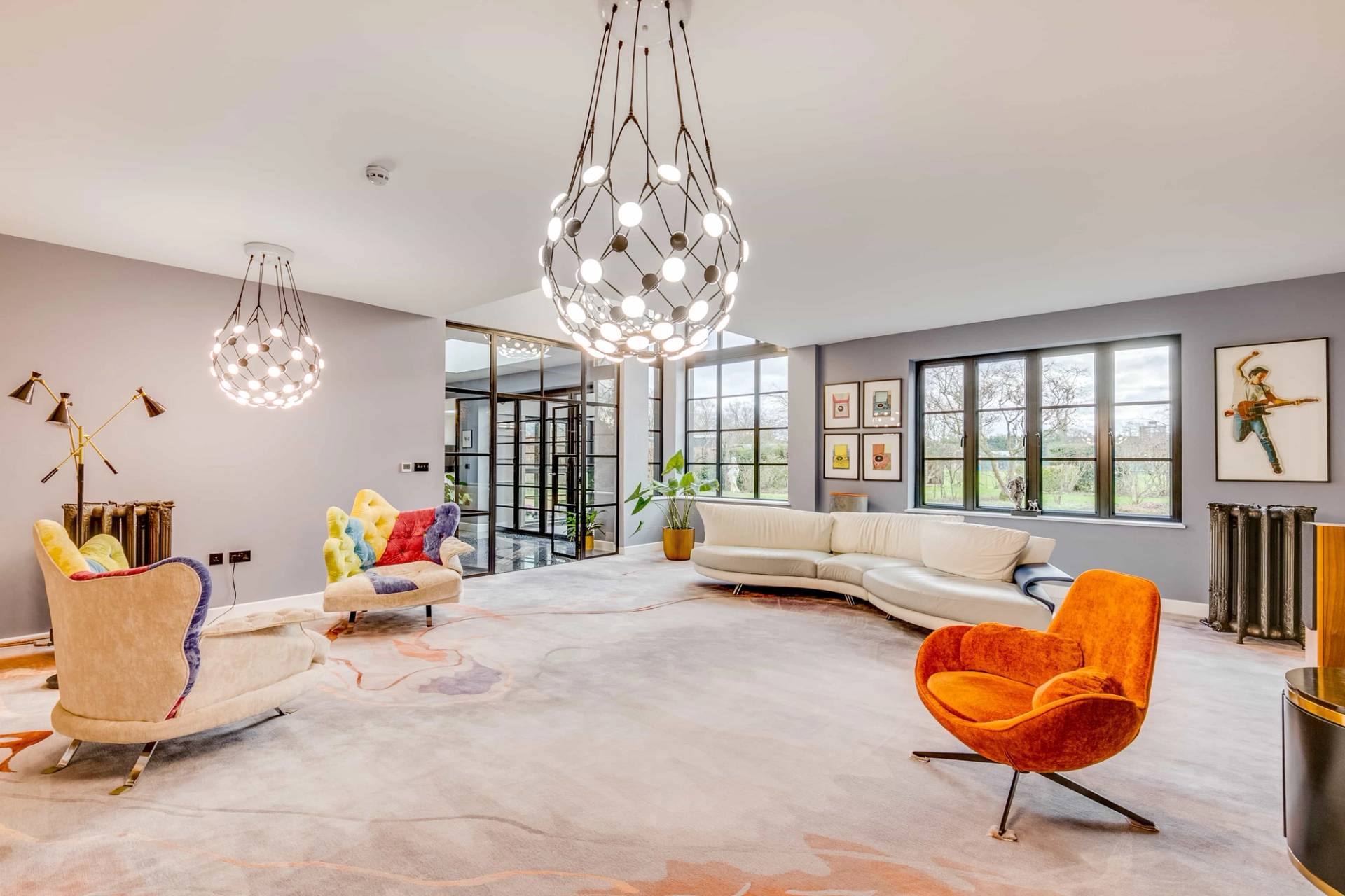 Open-plan reception room featuring rainbow upholstery chairs, spherical glass chandelier, and book wall, Love Locations CB2.