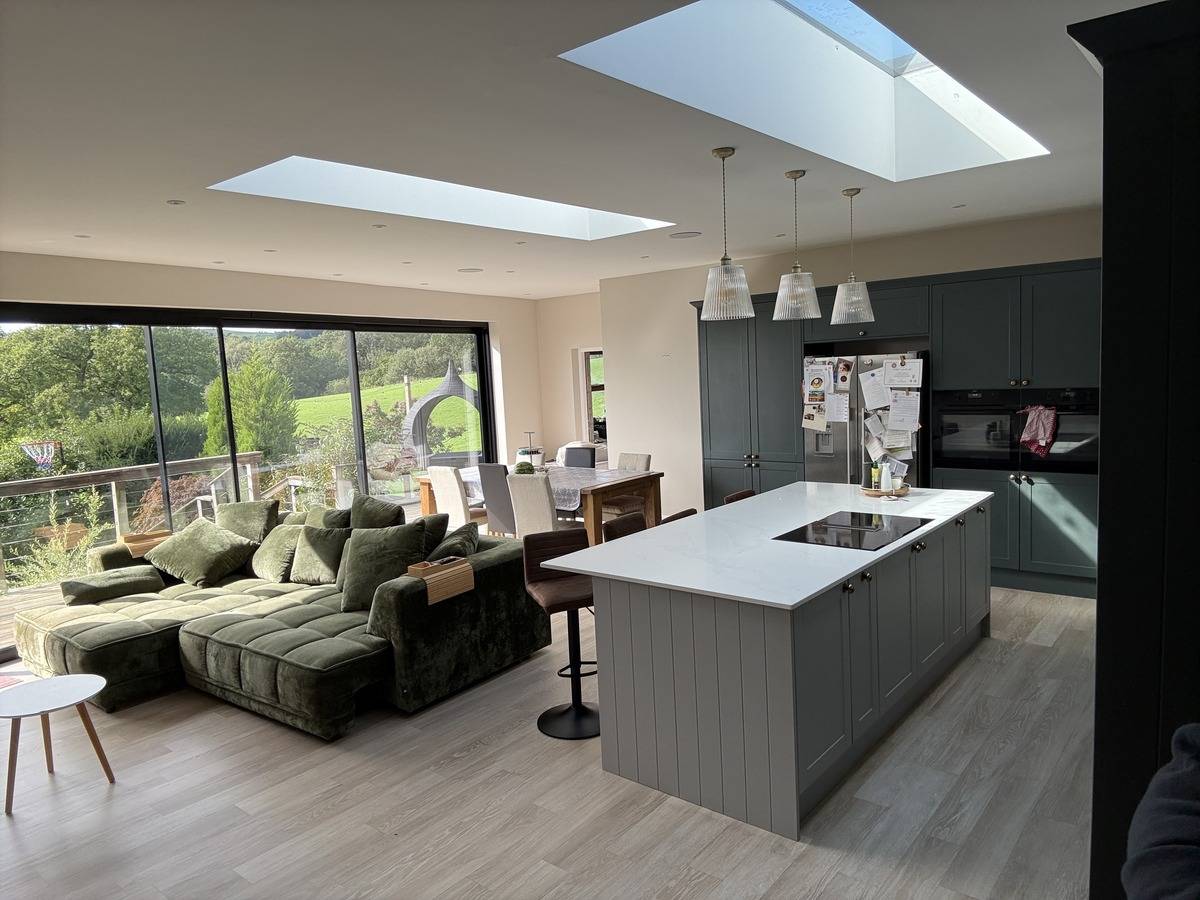 Spacious kitchen and living area shoot location in Stockport SK6 via Love Locations, showcasing skylights, modern island breakfast bar, and green sectional sofa.